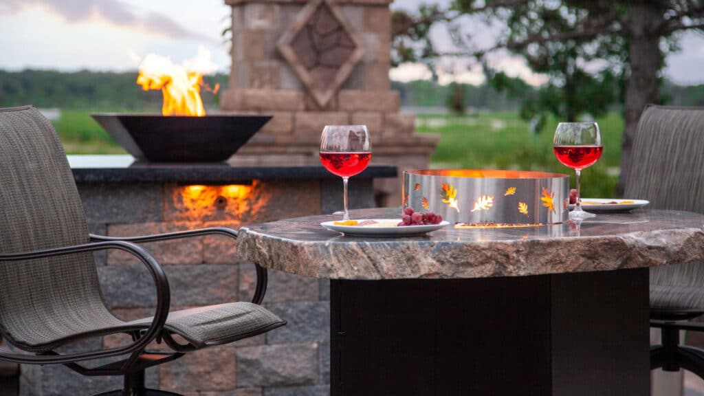 Elegant outdoor patio with granite-top table, fire feature, and built-in fire bowl—highlighting low maintenance landscaping that elevates relaxation and entertainment without intensive upkeep.