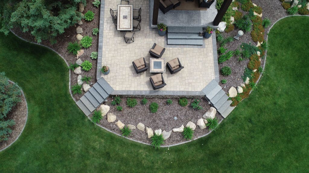 Aerial view of a paver patio with a seating area and well-maintained landscaping, perfect for outdoor relaxation.